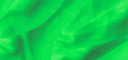 Blur of green fabric with delicate glowing threads gently flowing over the surface. The silky texture and smooth folds create a soft and luminous material, highlighted by intricate weavingの写真素材