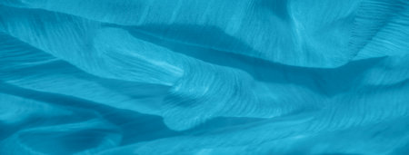 Blur of light blue fabric with soft, rippling folds and subtle texture. The natural flow of the fabric creates a calming and serene abstract design, highlighting the delicate material.の写真素材
