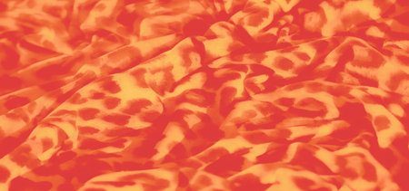 Blurred close-up of orange and yellow leopard-inspired fabric with bold spots. The swirling pattern...