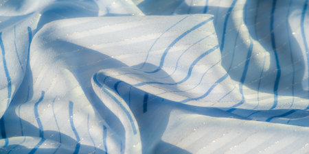Blurred soft blue fabric with shimmering stripes and gentle folds reflecting the soft light. The textile has a luxurious, airy feel, making it ideal for elegant backgrounds and fashion designの写真素材