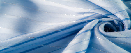 Blur of wavy blue fabric with subtle patterns and gentle ripples, capturing the interplay of light and texture, creating a serene and elegant visual flow of softness and glow.の写真素材