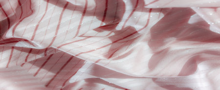Blur of soft pink fabric with striking red lines and silver highlights, gently folded to create a flowing texture, exuding both elegance and a soft shimmer under the light.の写真素材