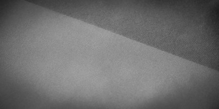 Blur of soft, draped grayscale fabric, with gentle folds and shadows creating a sleek, minimalistic design. The matte texture reflects subtle light, adding elegance to the composition.の写真素材
