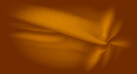Blur of rich orange fabric showing gentle folds and a smooth, seamless texture. The fabric's surface catches soft light, creating a dynamic flow that evokes warmth and luxurious comfort.の写真素材