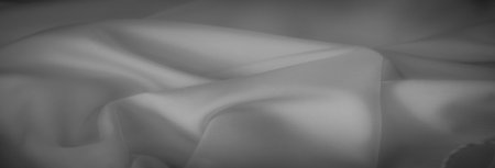 Blur of delicate folds in smooth grayscale fabric, with a subtle play of light enhancing the texture. The draped material offers a serene and calming visual effectの写真素材