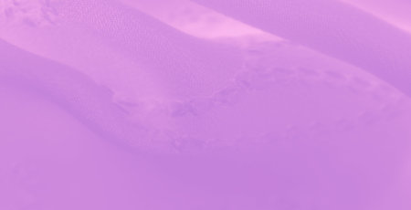 Blur of soft, lavender-colored fabric with intricate embroidery and flowing folds. The smooth...