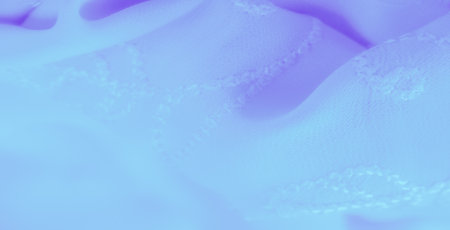 Blur of a soft blue fabric with embroidered swirling patterns. The delicate texture and intricate design create a graceful aesthetic, perfect for fashion or interior textile design.の写真素材