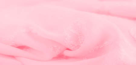 Blur of soft pink fabric with delicate embroidered floral patterns, creating a serene and gentle...