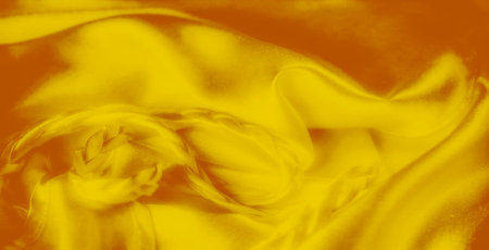 Blurred folds of yellow fabric with smooth textures and braided elements, creating a soft, elegant design. The interplay of light and shadows enhances the luxurious feel.の写真素材