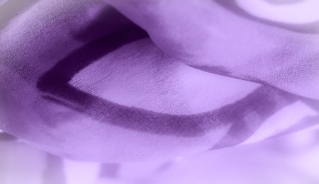 Blurred soft-focus image of purple fabric with intricate swirling patterns. The gentle curves and folds evoke a sense of flow, enhancing the overall softness and fluidity of the fabricの写真素材