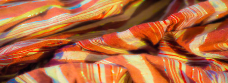 Blur of soft brown fabric with shimmering red and white stripes, artfully arranged in natural folds....