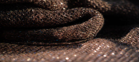 Blur of a rich, textured fabric in deep tones, enhanced by twinkling reflections from metallic...