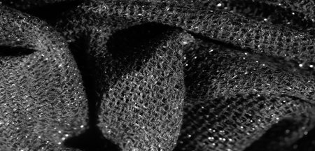 Blur of shimmering black fabric with intricate textures, capturing light reflections in a soft and elegant manner. The folds create a flowing, luxurious impression.の写真素材