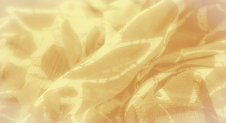 Blur of yellow fabric with detailed abstract patterns, gently folded to create soft layers and depth. The smooth surface and intricate design lend a sophisticated, elegant touch to the fabric'sの写真素材