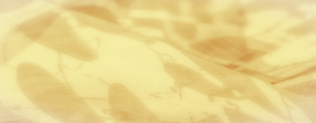 Blurred close-up of yellow fabric with subtle stirrup-like patterns. The fabric's smooth texture and...