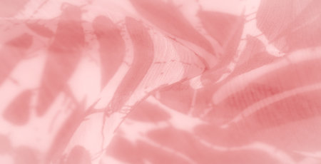 Blurred pink fabric with abstract floral-like designs. The sheer material drapes softly, creating intricate patterns and reflecting gentle light that enhances its soft, ethereal texture.の写真素材