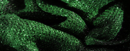 Blurred textured green fabric with a stunning glitter effect, highlighted by bright sparkles and...