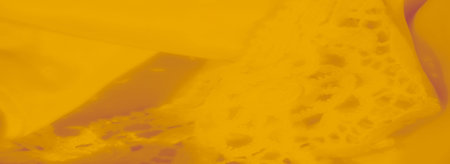Blurred view of yellow lace fabric emphasizing the detailed floral patterns and soft texture,...
