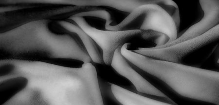 black, Blur of wavy folds in grayscale fabric, showing soft texture with a smooth flow of lines. The play between light and dark tones creates a captivating visual with a minimalist aesthetic.の写真素材