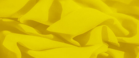 Blurred yellow fabric with soft folds (Image 1) Blur of vibrant yellow fabric displaying smooth, folded textures. The soft creases and fabric's flowing movement create a brightの写真素材