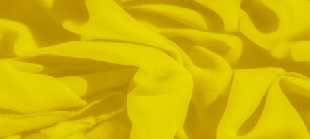 Blur A soft and delicate arrangement of yellow fabric folds, creating an abstract pattern of light and shadow. The vibrant hue and smooth texture add depth to the flowing design.の写真素材