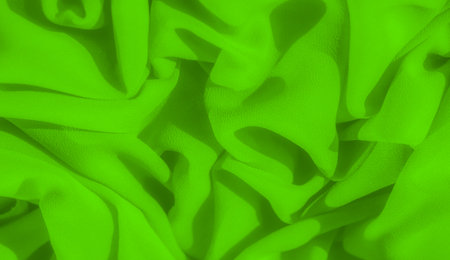 Blur folds of neon green fabric create a smooth, soft texture with shadows and highlights enhancing the depth. The close-up view emphasizes the intricate weave and vibrant color of the fabric.の写真素材