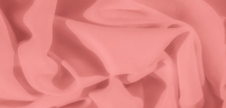 Blurred soft peach fabric with gentle, flowing folds and a smooth texture. The elegant fabric creates a serene and tranquil appearance, with shadows adding depth and contrast to the scene.の写真素材