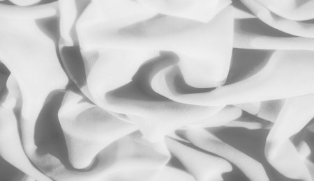Blur of light and shadows playing across the soft folds of gray fabric. The creases and smooth texture create an elegant and minimalistic abstract design.の写真素材