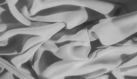 Blurred soft folds of fabric in grayscale create a gentle, fluid appearance. The shadows create a dynamic interplay of light and dark, enhancing the smoothness and elegance of the material.の写真素材