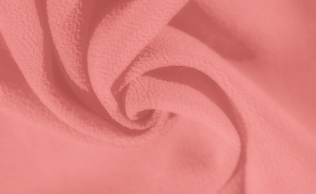 Blur of coral fabric delicately gathered in multiple layers, presenting a soft, elegant texture with subtle waves. The smooth folds highlight the gentle, pastel pink tone.の写真素材