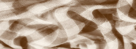 Blur of a fabric with subtle plaid patterns and sepia shading. The intricate textures and soft light reflections on the woven material give it a vintage, cozy appeal with visible thread details.の写真素材