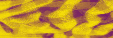 Blur: Close-up of yellow textured fabric with bold checkered patterns. The fabric folds enhance its textured weave, creating an interesting and abstract look with gentle purple undertones.の写真素材