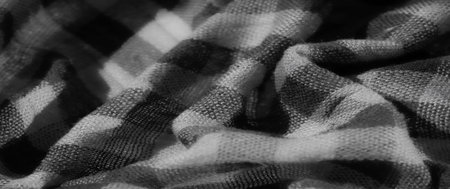Blur of a soft checkered fabric in grayscale tones, emphasizing the smooth folds and intricate woven...