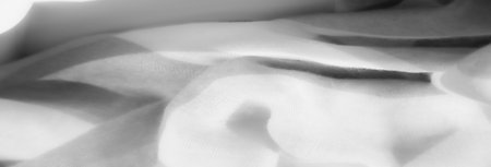 Blur of textured white fabric with gentle folds, highlighting its softness and flowing nature. The layers and smooth lines create an elegant and delicate appearance.の写真素材