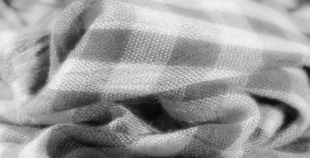 Blur. A textured grayscale fabric with a checkered design, gently draped in soft folds, offering a visual of its intricate weave and minimalist pattern.の写真素材