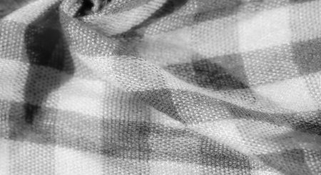 Blur. A gray and white checkered fabric displays its intricate texture and soft folds in this close-up image. The interplay of shadows and highlights adds depthの写真素材