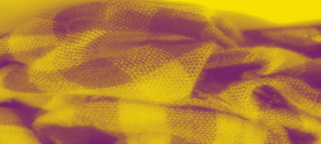 Blur of a folded yellow checkered fabric, with intricate weave and soft texture. The warm, bright...