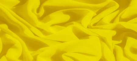 Blurred folds of bright yellow fabric form soft waves and texture, creating a vibrant and energetic visual effect. The smooth, flowing curves add a sense of motion and fluidity to the compositionの写真素材