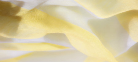 Blur of smooth yellow and white fabric, with gentle waves and light interplay creating a serene atmosphere. The fabric's soft texture and graceful folds reflect a tranquil, peaceful feelの写真素材