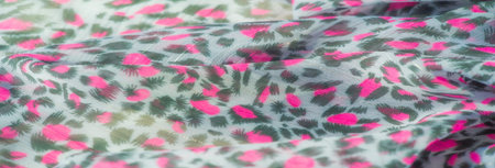 Blur of textured, sheer fabric with vibrant pink motifs on a gray base. The play of color and translucency offers a striking visual for textile or fashion projects.の写真素材