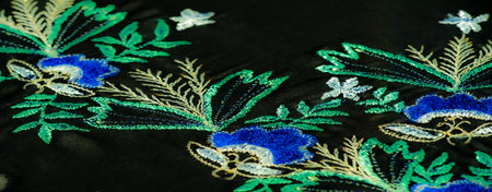 Blur of rich blue fabric highlighted by intricate floral embroidery, capturing each leaf and petal in fine detail, lending a sense of depth and luxury to the textile.の写真素材