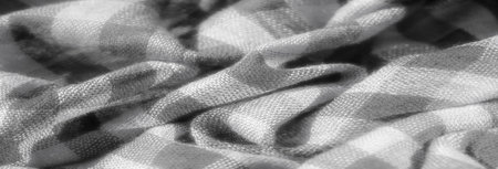 Blur. A close-up of a soft, grayscale textured fabric, featuring a crisscrossing checkered pattern with smooth folds and gentle light reflections.の写真素材