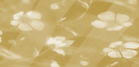 Blur The close-up captures the flowing texture of yellow fabric with soft light reflections,...