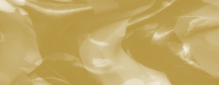 Blur of soft yellow fabric delicately twisted, catching the light to reveal a smooth, gentle texture with warm undertones, evoking elegance and softness.の写真素材