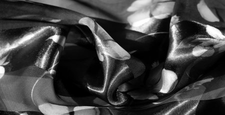 Blur of grayscale fabric with soft floral patterns. Transparent and opaque stripes alternate, creating a layered look with scattered flowers for a delicate, textured feelの写真素材