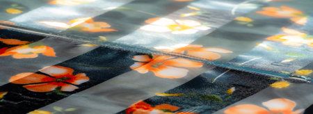 Blur: Smooth, transparent fabric with black and floral accents in vibrant orange and yellow. The gentle folds and subtle sparkle add depth to this elegant textileの写真素材