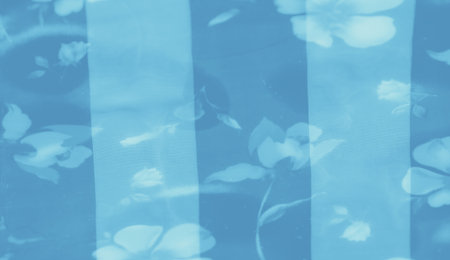 Blur of blue fabric featuring flowing textures and delicate floral elements, offering a calm, airy aesthetic with layered patterns that provide a refined, gentle backdrop.の写真素材