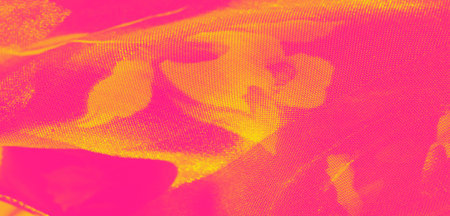 Blur of intertwined pink and yellow fabric with a radiant shine, featuring floral impressions and smooth, translucent folds that exude warmth and vibrancy.の写真素材