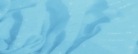 Blurred image of smooth light blue fabric, capturing intricate folds and a light shimmer that creates a delicate, serene appearance, perfect for a tranquil and artistic background.の写真素材