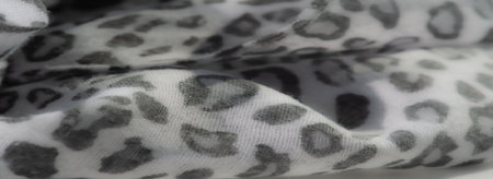 Blur effect highlights the gray and white leopard-like print on light fabric, emphasizing softness...